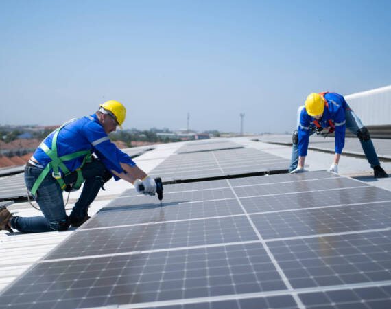 Beide Techniker installieren Sonnenkollektoren auf dem Dach des Gebäudes